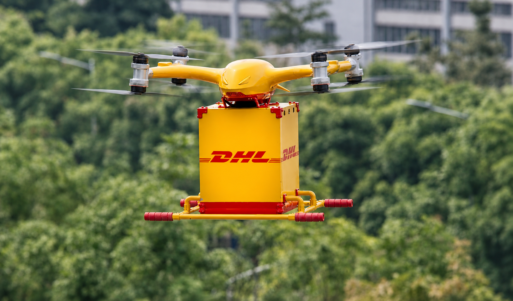 Gelbe Transportdrohne mit Paket im Flug